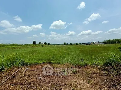 Expansive green field under a clear blue sky, perfect for development opportunities.