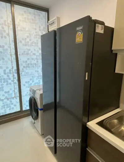 Modern kitchen with sleek black fridge and washing machine