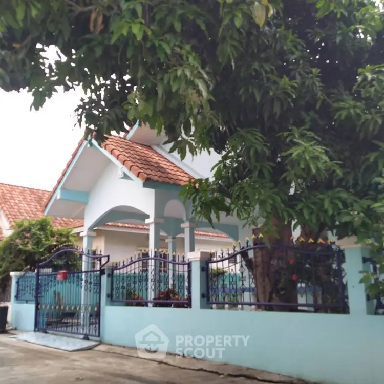 Charming blue house with tiled roof and lush garden in a serene neighborhood.