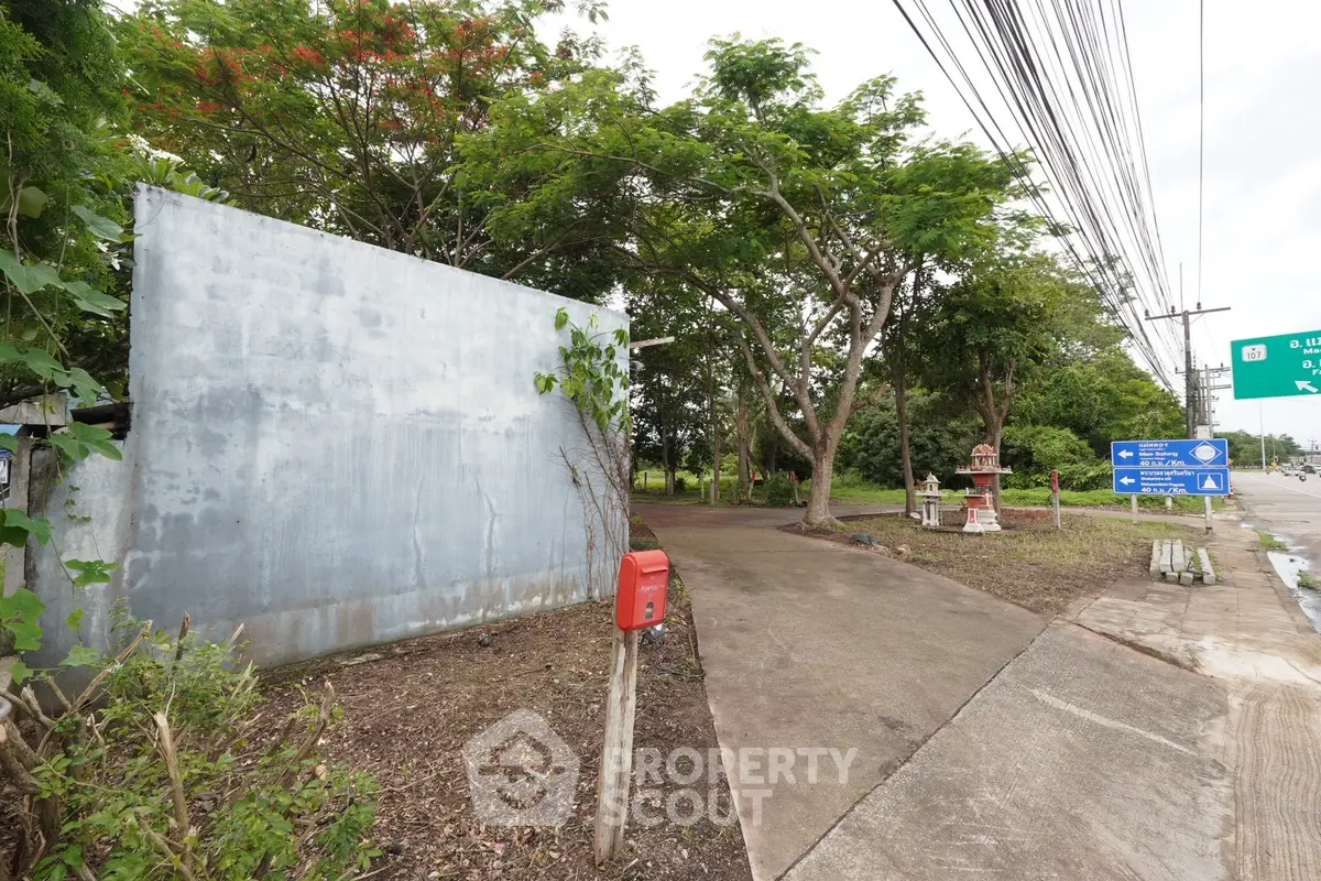 Charming entrance to a serene property with lush greenery and a welcoming driveway.