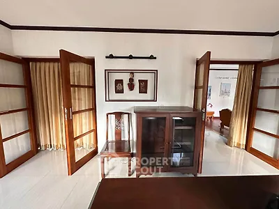 Elegant living room with wooden furniture and glass doors, showcasing a classic interior design.