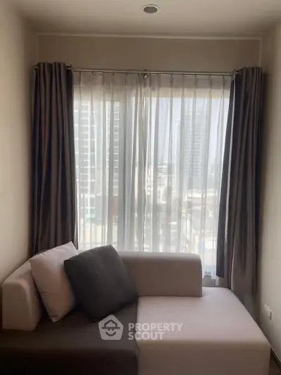 Cozy living room with modern sofa and city view through large window.