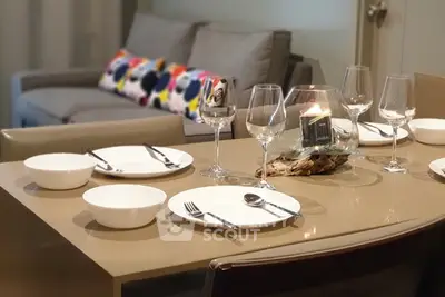 Elegant dining area with modern table setting and cozy sofa in the background.