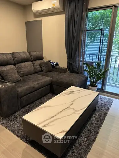 Modern living room with plush sofa and marble coffee table near balcony.
