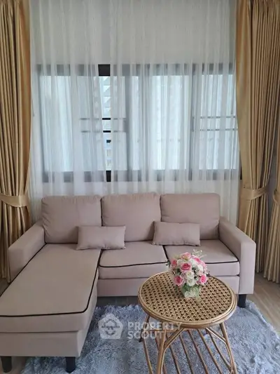Elegant living room with beige sofa, sheer curtains, and a stylish wicker coffee table.