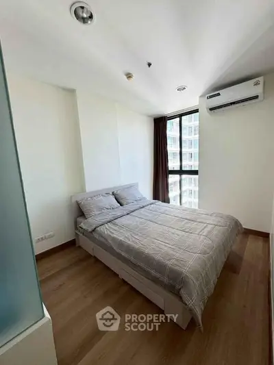 Modern bedroom with large window and air conditioning in a high-rise apartment.