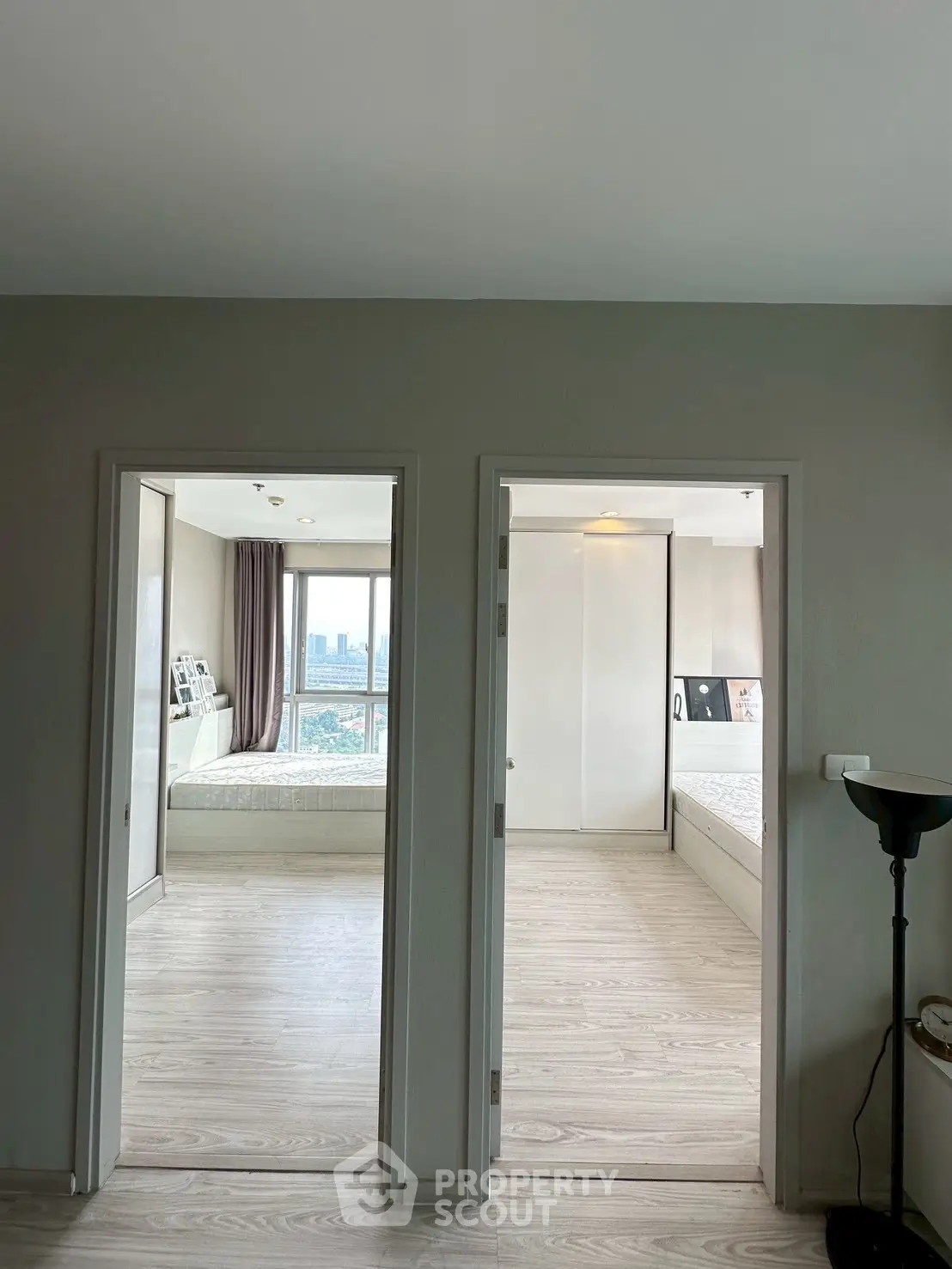 Modern apartment interior with two bedrooms and city view, showcasing sleek design and natural light.