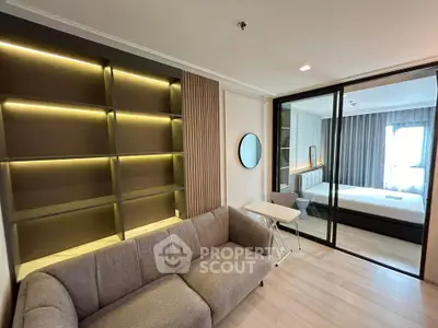 Modern living room with stylish shelving and cozy sofa adjacent to a bedroom with glass partition.