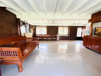 Spacious living room with wooden furniture and large windows in a bright, airy home.