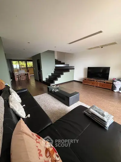 Spacious modern living room with sleek black sofa and stylish staircase