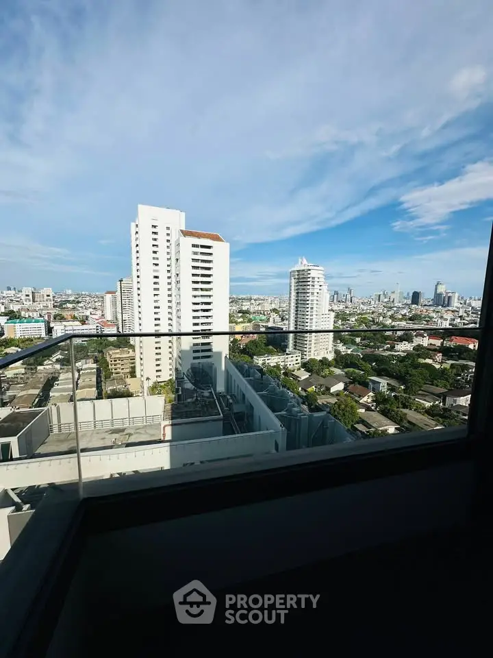 Stunning cityscape view from a high-rise balcony with clear blue skies.