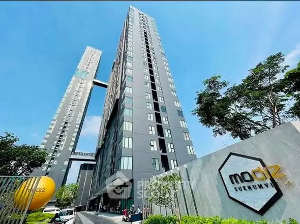Modern high-rise building with sleek design and lush greenery in urban setting.