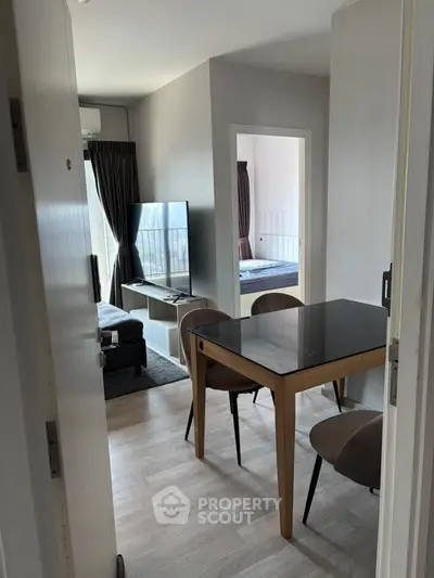 Modern apartment interior with open living and dining area, featuring sleek furniture and natural light.