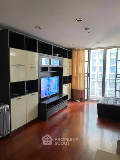Spacious living room with modern entertainment center and large windows offering city views.