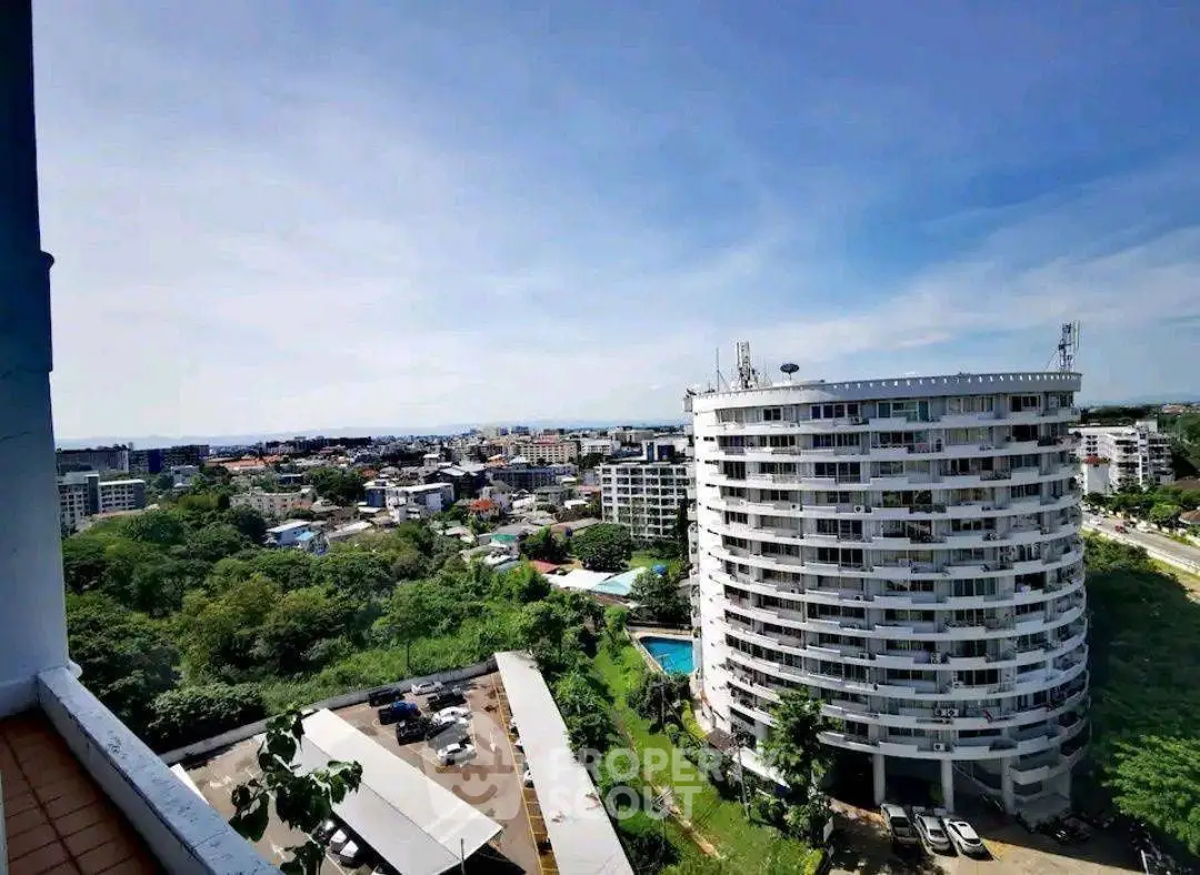 Stunning cityscape view from high-rise balcony overlooking modern architecture and lush greenery.
