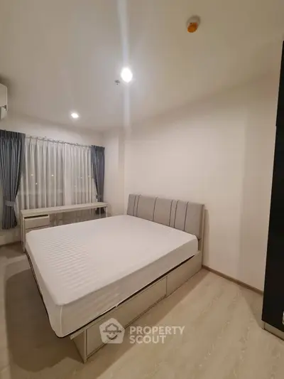 Modern bedroom with minimalist design and large window for natural light.