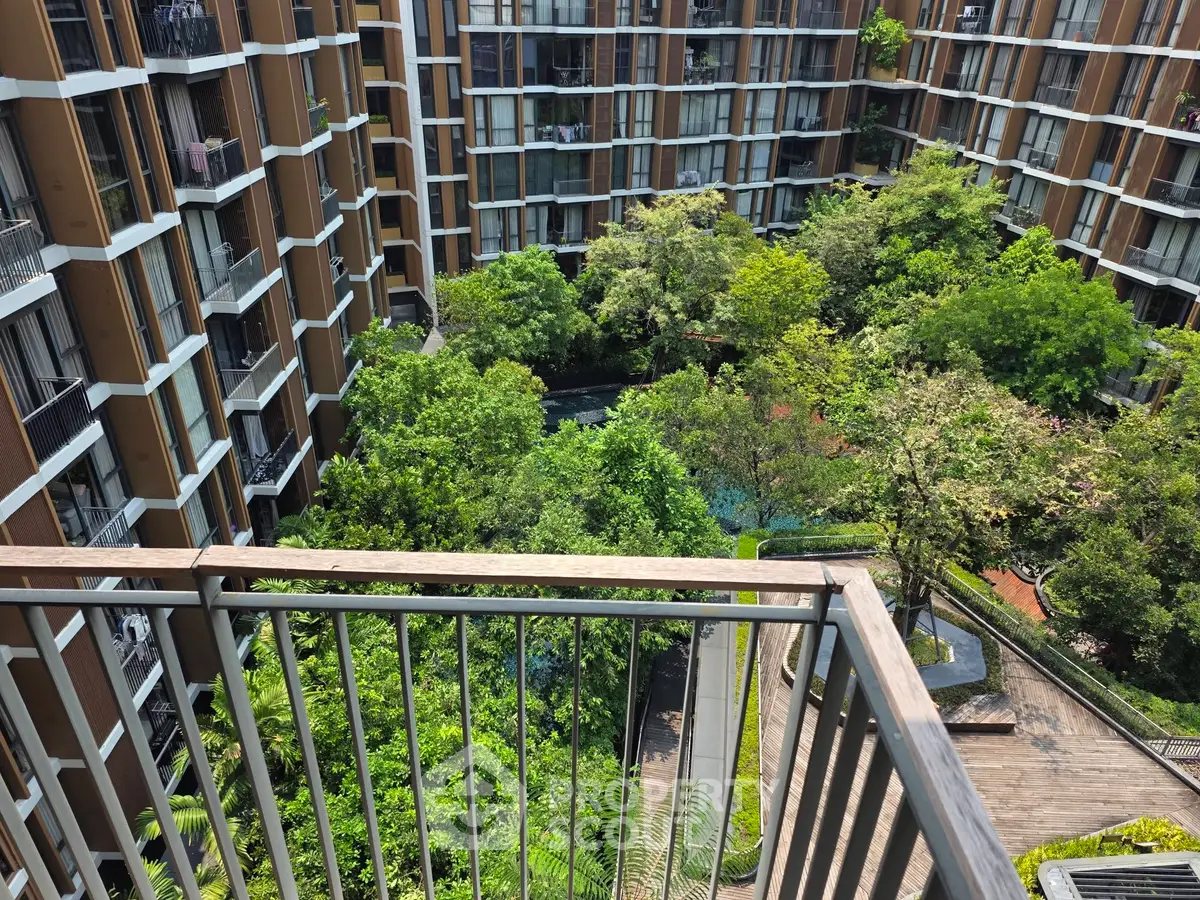 Stunning view from a balcony overlooking lush green courtyard in modern apartment complex.