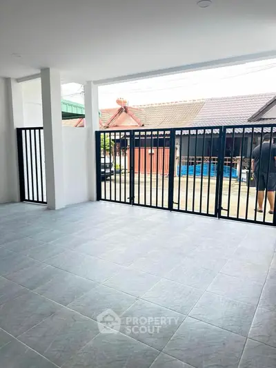 Spacious tiled patio with modern black metal gate and view of neighborhood houses.
