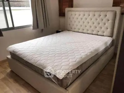 Spacious bedroom with elegant upholstered bed and natural light.