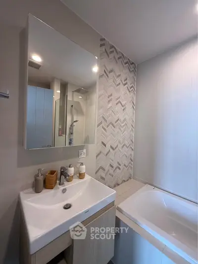 Modern bathroom with stylish sink and bathtub, featuring elegant tile design.