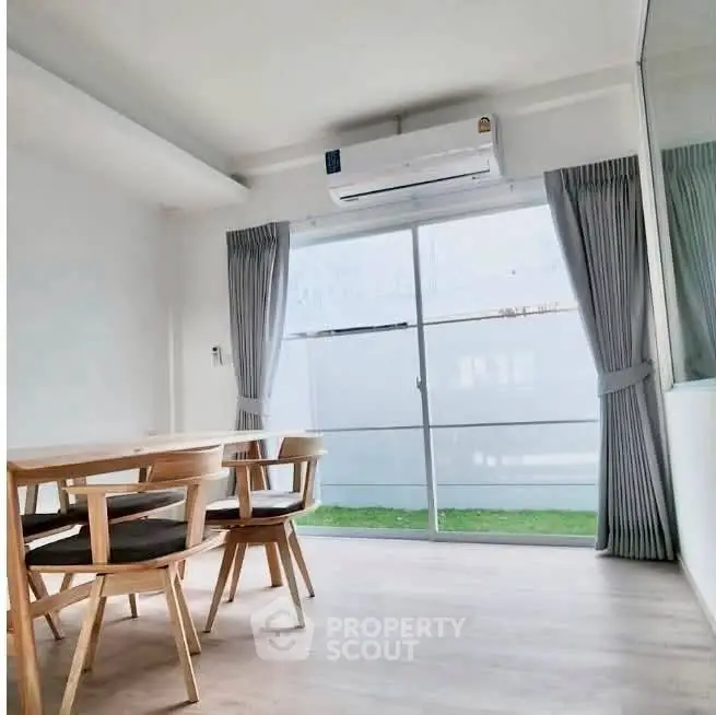 Bright dining area with modern wooden furniture and large window view.