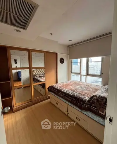 Cozy bedroom with mirrored wardrobe and city view window