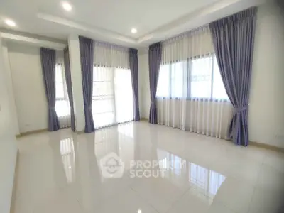 Spacious empty room with large windows and elegant curtains