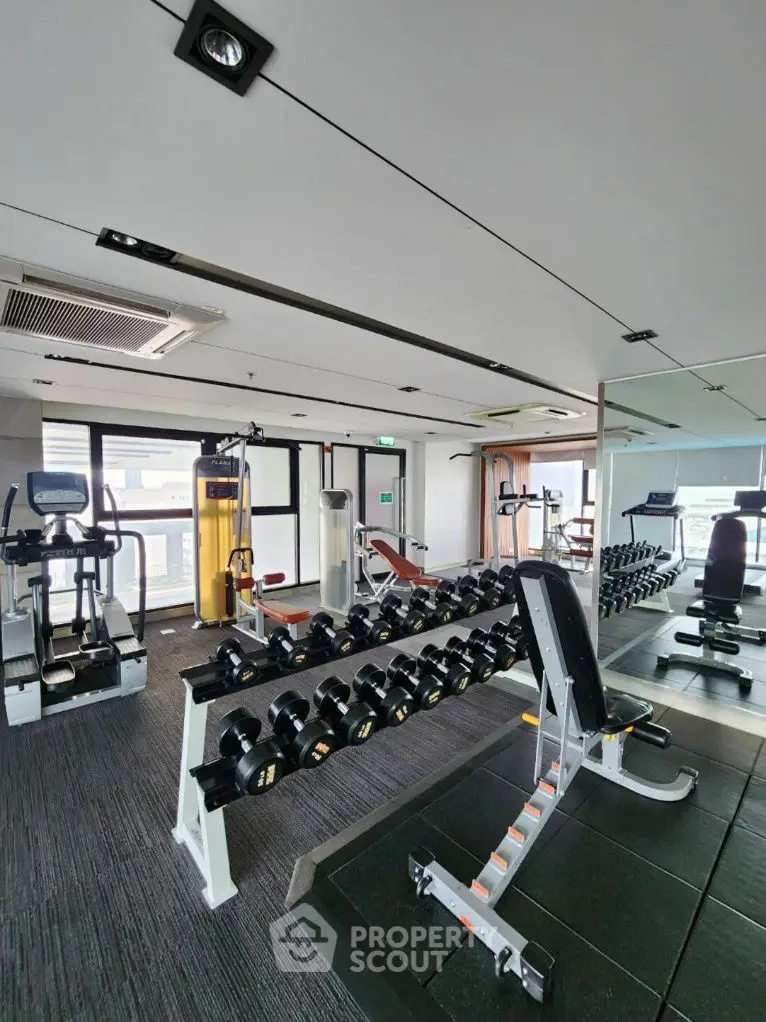 Modern gym with state-of-the-art equipment and panoramic windows in luxury residential building.
