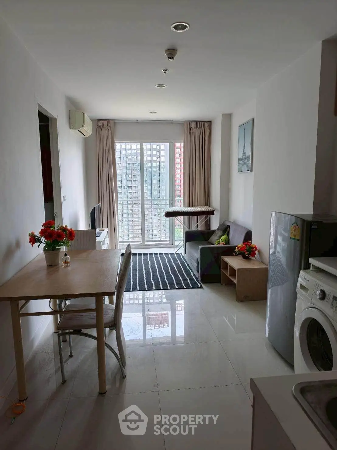 Modern apartment living room with dining area and city view, featuring sleek furniture and natural light.