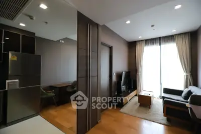 Modern living room with sleek furniture and natural light, adjacent to a compact kitchen area.
