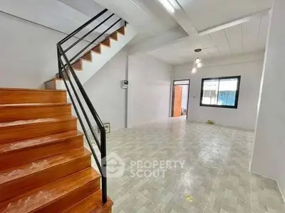 Spacious open-plan living area with modern staircase and large window.