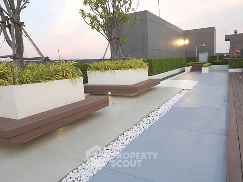 Modern rooftop garden with stylish planters and seating area at sunset.