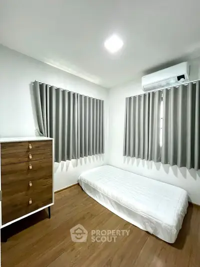Cozy minimalist bedroom with single bed and modern air conditioning unit.