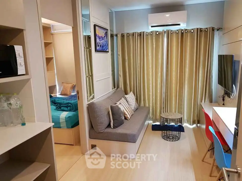 Modern compact living room with cozy sofa, TV, and air conditioning, adjacent to a small bedroom.