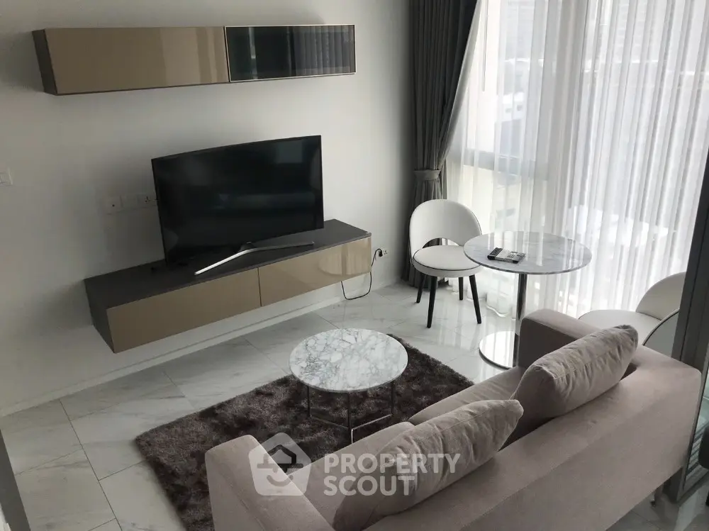Modern living room with sleek furniture and large TV, featuring marble tables and a cozy sofa.