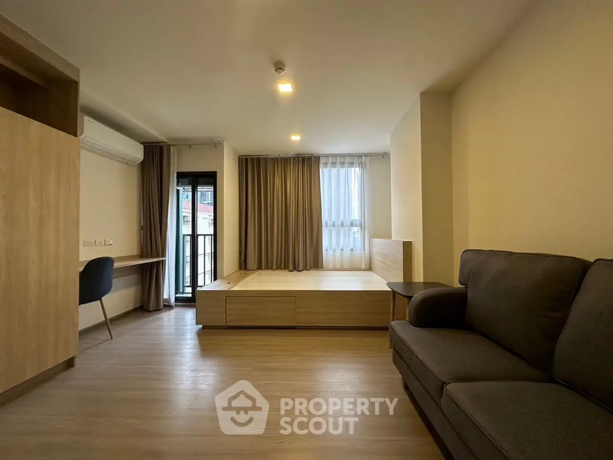 Modern studio apartment with cozy living area and balcony access.