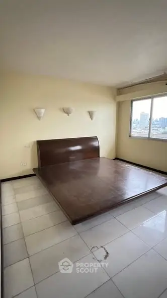 Spacious bedroom with city view and elegant wooden bed frame.