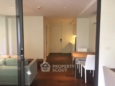 Modern apartment interior with open layout, featuring a cozy living area and dining space with wooden flooring.