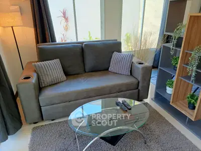 Modern living room with stylish sofa, glass coffee table, and natural light from large windows.