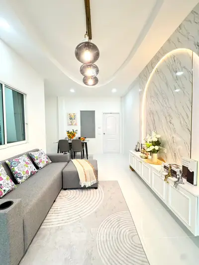 Modern living room with stylish decor and cozy seating area, featuring elegant lighting and marble accent wall.