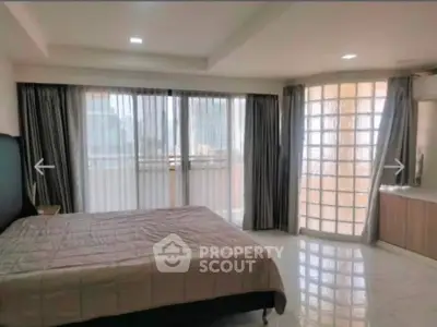 Spacious bedroom with large windows and modern decor in a luxury apartment.