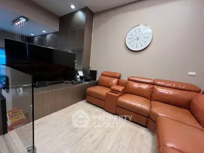 Modern living room with leather sectional sofa and wall clock, featuring sleek wooden cabinetry and large TV.