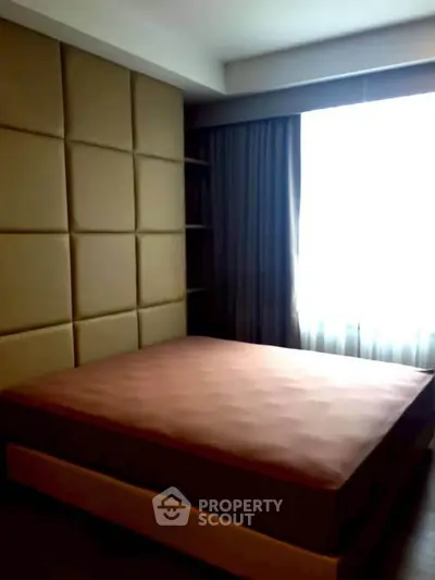 Luxurious bedroom with padded wall and large window for natural light