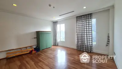 Spacious empty room with wooden flooring and large windows, ideal for customization.