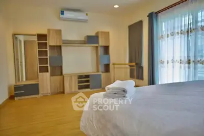 Spacious bedroom with modern wooden furniture and large window