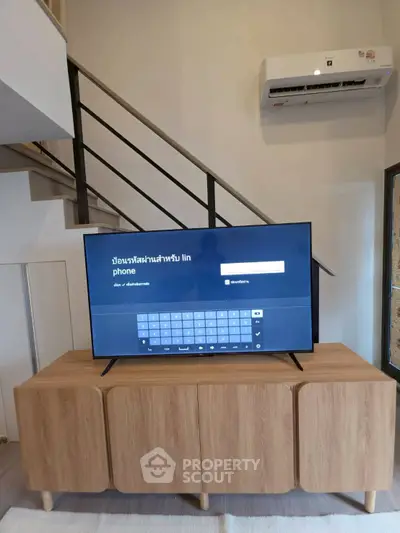 Modern living room with stylish wooden TV stand and staircase, featuring sleek air conditioning unit.