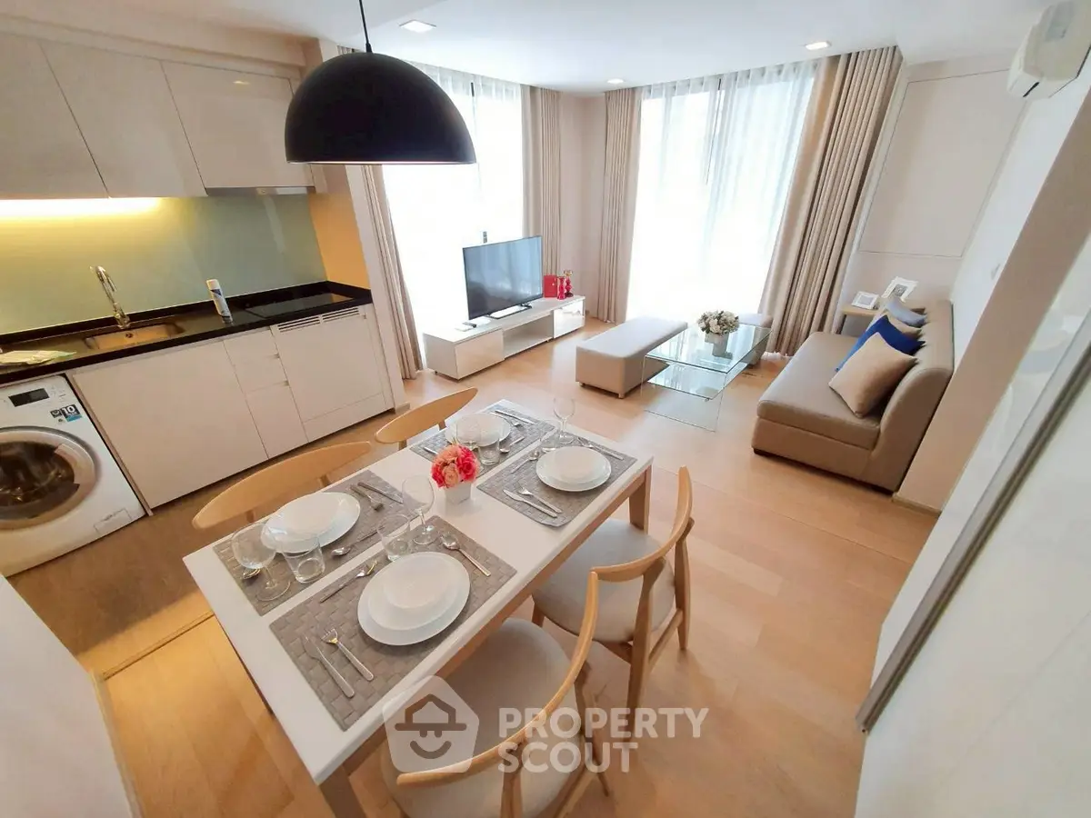 Modern open-plan living room with kitchen, dining area, and cozy seating, featuring stylish decor and natural light.