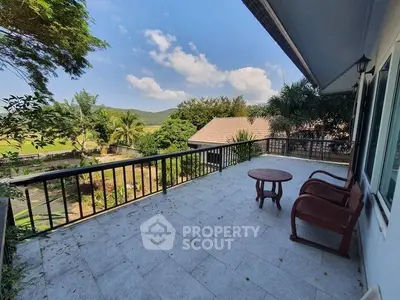 Spacious balcony with scenic view of lush greenery and distant hills.