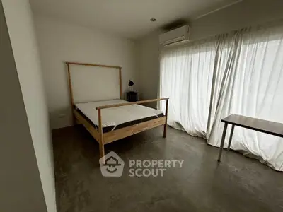 Minimalist bedroom with wooden bed frame and large window for natural light.