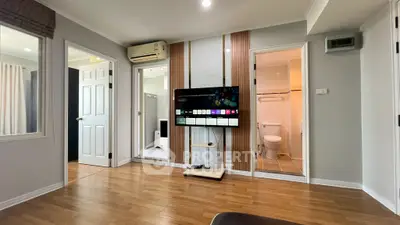Modern living room with wooden flooring, wall-mounted TV, and access to bathroom and bedroom.